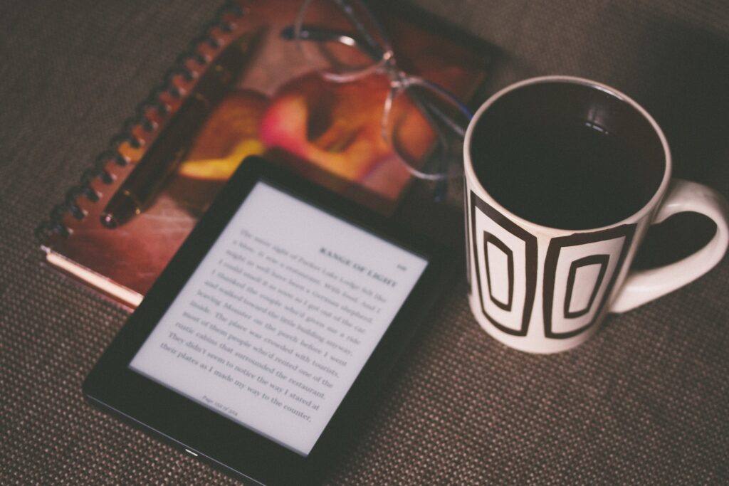  A reading tablet sitting on a table with a cup of coffee and reading glasses