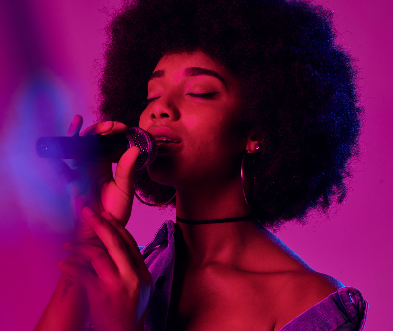 Black woman with an afro singing into a mic