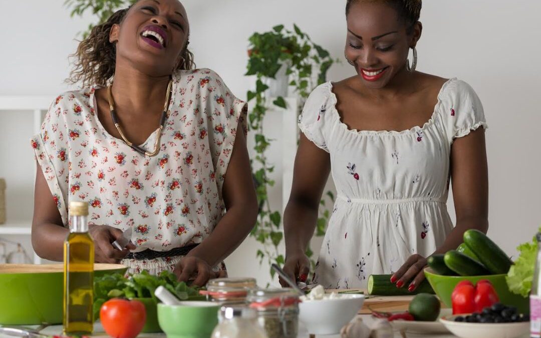 Two Black women in a kitchen cutting up vegetables
